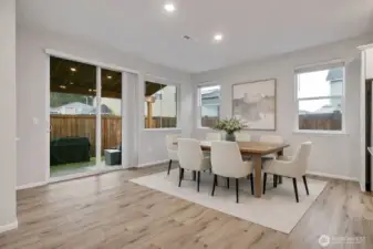 Bright dining area connected to the kitchen, leading to a private fenced and covered patio - Virtual stage.