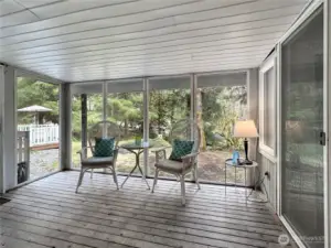The covered porch has a wall of windows for taking in the wooded surroundings in any weather