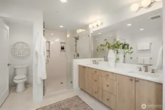 Primary en suite bathroom with dual vanities, water closet, standalone tub and large shower