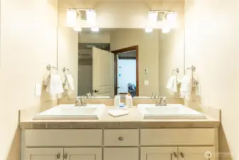 Primary bathroom has white cabinetry and double sinks.