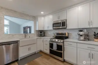 Beautiful white cabinetry, full height backsplash, and stainless appliances complement this kitchen.