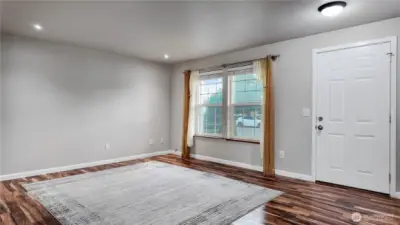 Spacious living room with updated flooring, large windows, and flexible layout options.