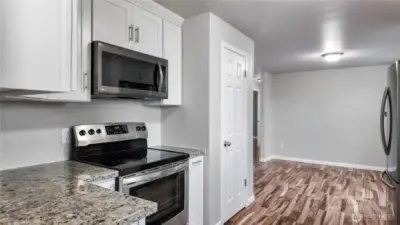 Kitchen cooking area with granite countertops, stainless steel range, and built-in microwave.