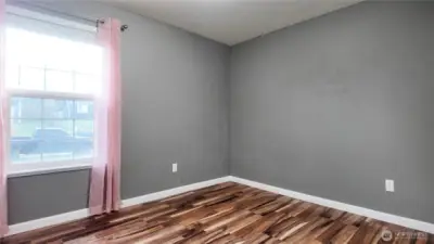 Bedroom featuring window, updated flooring, and neutral tones.