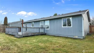 Rear exterior featuring a spacious deck and fully fenced yard, ideal for outdoor use.