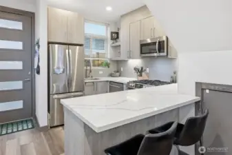 Modern kitchen with quartz countertops, stainless steel appliances, and bar seating for casual dining.