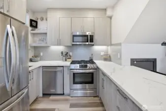 Stainless steel appliance package including gas range, refrigerator, and dishwasher paired with contemporary finishes.