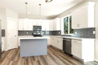 Bright Kitchen with clean lines, and an inviting layout. White cabinetry with soft close features and beautiful tiled backsplash gives it a modern-but-warm balance