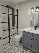 Upgraded bathroom includes a glass shower door, 8 spout shower head, tile to the ceiling in the shower, custom tiles on the floor and new cabinet with quartz top and all new fixtures.