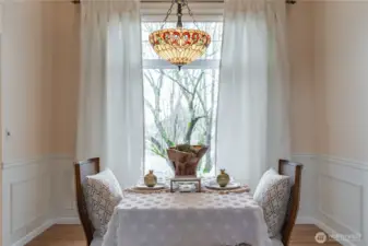 Mature landscaping frames the dining space. Wainscotting wraparound adds to the beauty. Hanging light conveys with home.