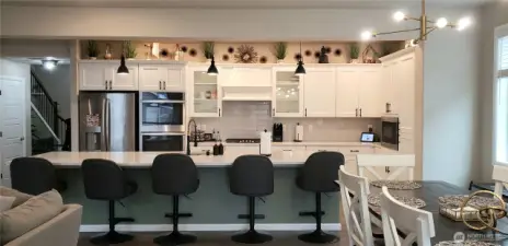 Another view of the Huge Great Room Island Kitchen showing all Vinyl Plank Flooring,White Cabinets, all Stainless Appliances including Double Oven, Long Breafast Bar, Freshly Painted Through Out,  and Partial Dining Room.