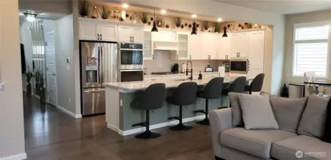 View of the Huge Great Room Island Kitchen showing all Vinyl Plank Flooring,White Cabinets, all Stainless Appliances including Double Oven, Long Breakfast Bar and  Freshly Painted Through Out.