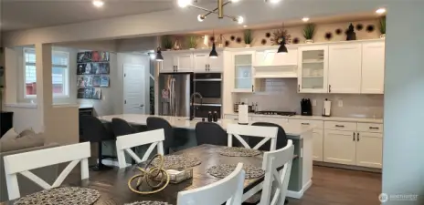 VAnother view of the Huge Great Room Island Kitchen showing all Vinyl Plank Flooring,White Cabinets, all Stainless Appliances including Double Oven, Freshly Painted Through Out,  and Partial Dining Room.