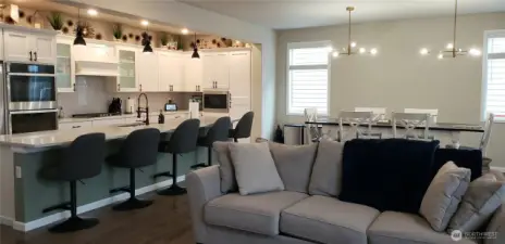 A Different View from the Living Room Showing the Huge Great Room Island Kitchen showing all Vinyl Plank Flooring,White Cabinets, all Stainless Appliances including Double Oven, Freshly Painted Through Out,  and the Dining Room.