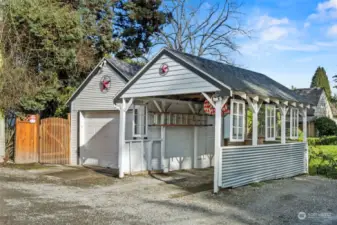 Carport area with glass art sitting along side garage. electric charging port present.