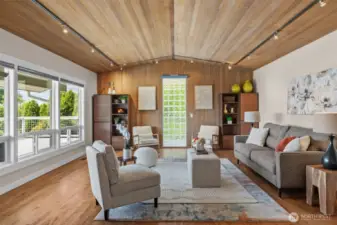 The expansive and inviting living room stuns with newly installed hardwoods, cedar-lined vaulted ceilings, and walls of windows framing the view—yes, even electronic blinds!