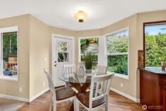 Sun filled dining nook with bay windows and direct access to the deck, making indoor and outdoor living easy, with a peaceful outlook to the fenced yard.
