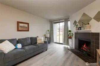 Living room with abundant natural light and a spacious, open feel. Enjoy the cozy warmth of the wood burning fireplace. SLider leads out to the back patio and storage room. Additionally, the unit enjoys close proximity to the community pool for Summer enjoyment!