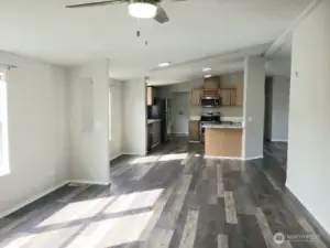 Another Opposite View Picture of the Huge Kitchen Showing Ample Cabinet Space, Newer Counter Tops, LED Lighting, All Stainless Appliances Including Built In Microwave, Glass Top Stove Oven, Trim, and Vinyl Plank Flooring Looking into the Kitchen And Ding Room from the Second Living Room.