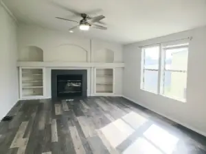 Picture of the Spacious Second Living Room with a Wood Burning Fireplace, Mantle and Cabinet Surround. Newer  Trim, and Vinyl Plank Flooring Looking from the Dining Room.