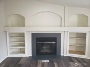 Another Close up Picture of the Spacious Second Living Room with a Wood Burning Fireplace, Mantle and Cabinet Surround. Newer  Trim, and Vinyl Plank Flooring.