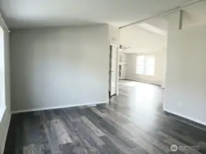 Picture of the Enormous Main Living Room from the the From the Front Entry Door Showing the Vinyl Plank Flooring and Newer Paint and Trim Looking at the Second Living Area and the Primary Bedroom.