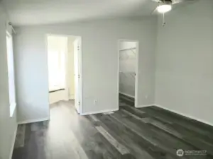 Another View of the Huge Primary Master Bedroom from the Double Entry Doors Showing Newer Trim, and Vinyl Plank Flooring and Looking at the Primary Bath Room and Walk In Closet.