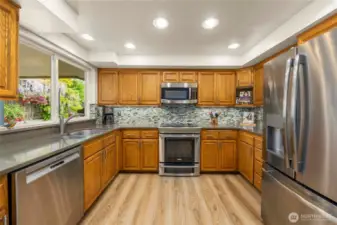 Efficient U-Shaped Kitchen with LVP flooring, SS Appliances, Solid Wood Cabinets, Quartz Counters and Tile Backsplash.  The Double Window Above the Sink Overlooks the Gorgeous Side Yard.