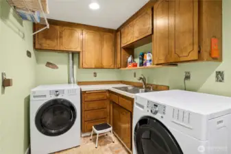 Fully-equipped laundry room with lots of cupboards, hanging space and laundry sink