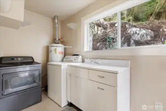 The mud room with it's own side entrance houses the laundry area and offers a utility sink, storage, and a window overlooking the hillside- an incredibly useful space for daily life.