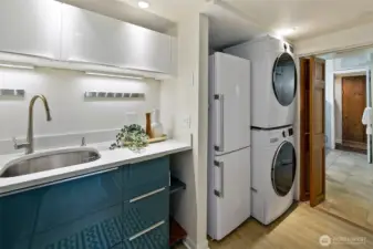 Stacked laundry is right outside the 3/4 bath, and the wood door beyond is the sauna.