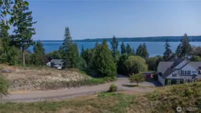 The stunning views of Hood Canal and the Cascade mountains from the potential building site on Lot 2! Power and cable are on the street, water is available, and a connection for the community drain field is located on the parcel where the white house sits on the right.