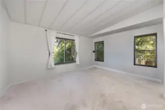 Primary bedroom w/ lots of windows and new carpeting.