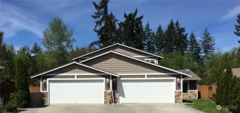 The well-kept duplex with plenty of parking space and a beautiful green backdrop.