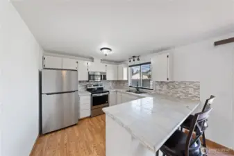 Kitchen w/ marble tile counters, tile backsplash, newer SS appliances