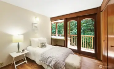 Bedroom 1 on the upper level with built-in desk and access to the creek-facing balcony.