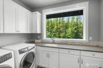 Upstairs laundry room with pretty views and utility sink.