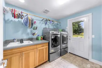 Spacious laundry room, with cabinets, sink, counter space, and access to the backyard.
