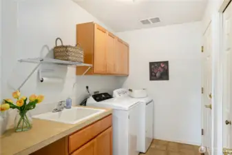 Conveniently located on the main floor, the utility room offers a deep sink, generous cabinets, and a closet for organized storage.