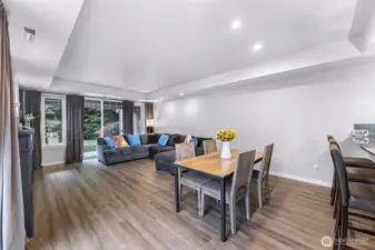 Spacious great room with large windows and sliding doors that bring in natural light and private green space views.