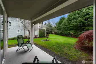 Covered patio that opens directly to the shared lawn and landscaped green space, offering a peaceful outdoor setting.