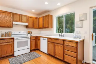 Beautifully maintained kitchen featuring solid oak cabinets, newer bamboo floors, new stove (2023), and new dishwasher (2022). Enjoy preparing meals with serene views of the greenbelt.