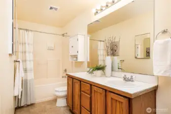 Primary en-suite bathroom features a shower and tub combination with dual vanities for convenience and comfort.