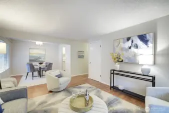 The living room flows directly into the large dining area with an oversized window and custom lighting.