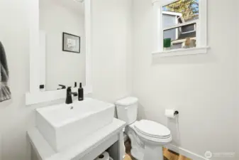 The downstairs bathroom, conveniently located off the office and entry, features a clean, modern design with a stylish vanity, contemporary fixtures, and natural light—ideal for guests or everyday use.