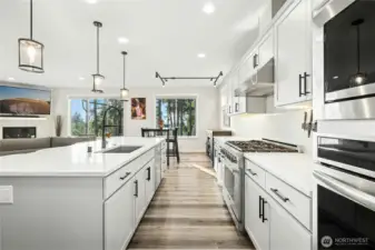 The beautifully designed kitchen features sleek cabinetry, modern appliances, and abundant counter space, all centered around a generous island ideal for gathering. Large windows frame serene views, bringing natural light and the beauty of the outdoors into this inviting, functional space.