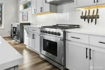This chef-inspired kitchen features a high-end gas range, sleek cabinetry, and a modern tile backsplash illuminated by under-cabinet lighting. Thoughtful details and premium finishes make it both a showpiece and a highly functional space for cooking and entertaining.