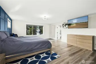 The primary bedroom offers generous space, modern finishes, and a calming color palette highlighted by a stylish accent wall. Large windows bring in natural light and peaceful Northwest views, creating a true retreat.