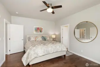 This light and airy primary suite features high ceilings, hardwood floors, and roomy walk-in closet with built-ins. The door on the right opens into the private ensuite bath.