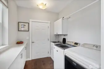 The laundry and mud room of your dreams! Located off the entry, with plenty of space for washer and dryer, sink, and handy folding counter with custom storage cabinets underneath. The door leads to the garage.
